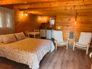 Innenraum der Holzhütte Drago: Doppelbett, Sessel und Küchenzeile