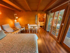 Chambre spacieuse avec table, fauteuils et grande fenêtre